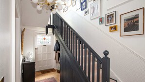A staircase with a black railing and a chandelier. There are framed pictures on the wall above the stairs. - Charming 3BD Oasis 3 Min Walk From Beach Front! (Dublin)