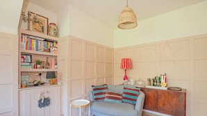 A cozy room with a sofa, a small table, a bookshelf, and a decorative lamp. - Charming 3BD Oasis 3 Min Walk From Beach Front! (Dublin)