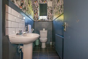 A bathroom with a white sink, toilet, and a window above the toilet. - Charming 3BD Oasis 3 Min Walk From Beach Front! (Dublin)
