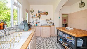 A kitchen with a large window, white tiles, and wooden cabinets. - Charming 3BD Oasis 3 Min Walk From Beach Front! (Dublin)