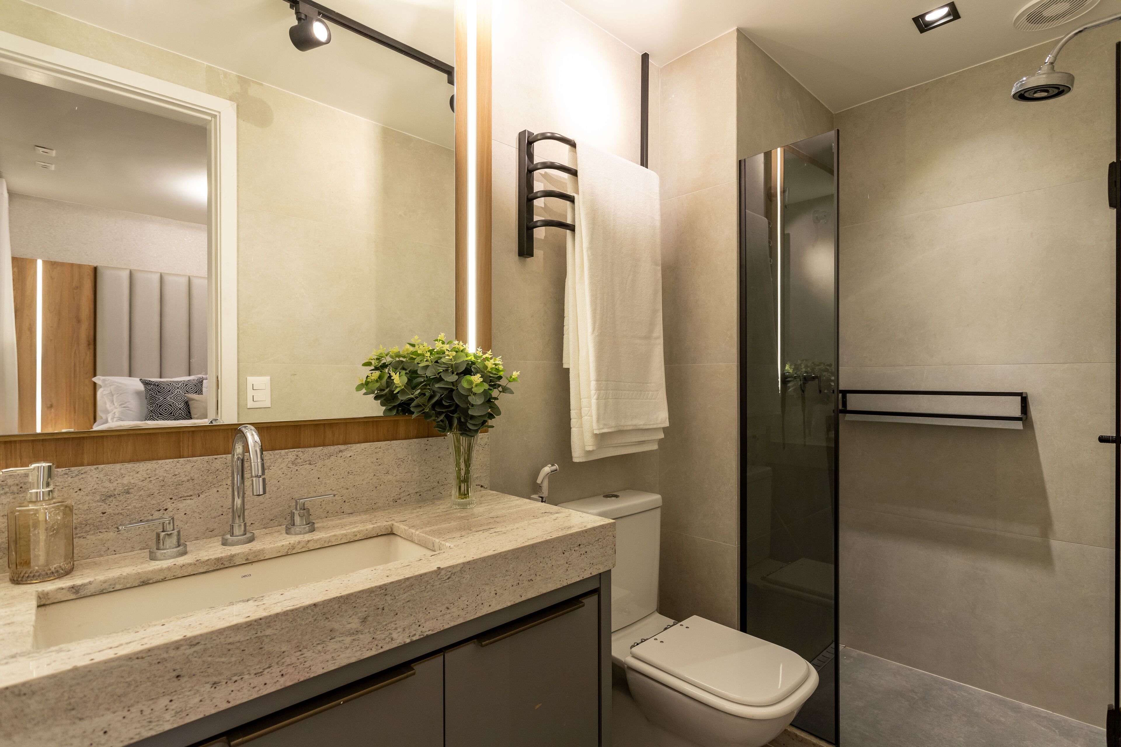 A modern bathroom with a granite countertop, a glass shower enclosure, and a toilet.