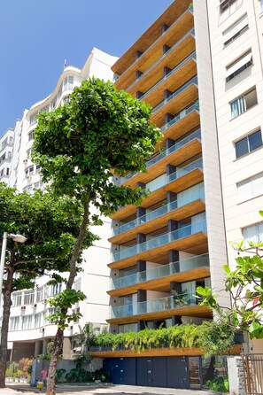 A multi-story building with balconies, a tree in front, and a clear blue sky. - Unhotel (Rio de Janeiro)