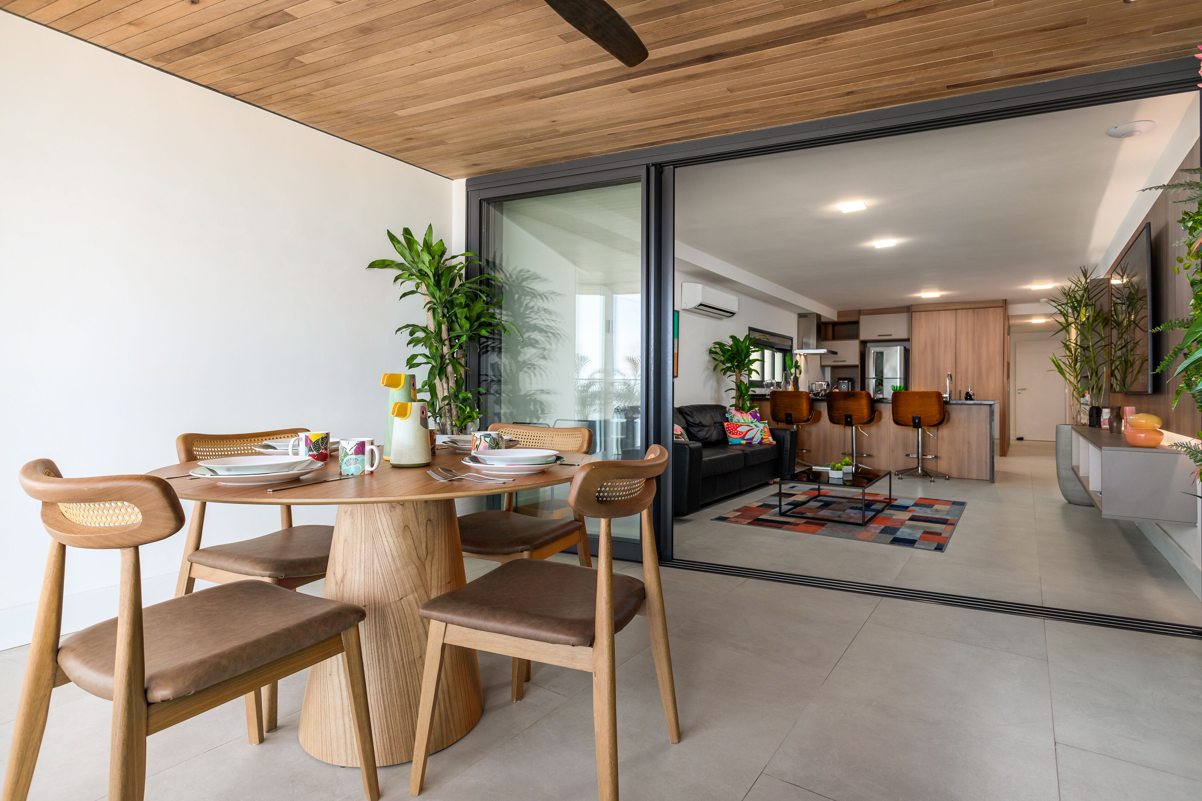 A modern dining area with wooden furniture and a glass partition leading to a kitchen.