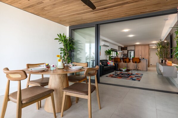 A modern dining area with wooden furniture and a glass partition leading to a kitchen.