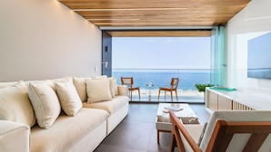 A modern living room with a sofa, chairs, a coffee table, and a view of the ocean. - Unhotel (Rio de Janeiro)