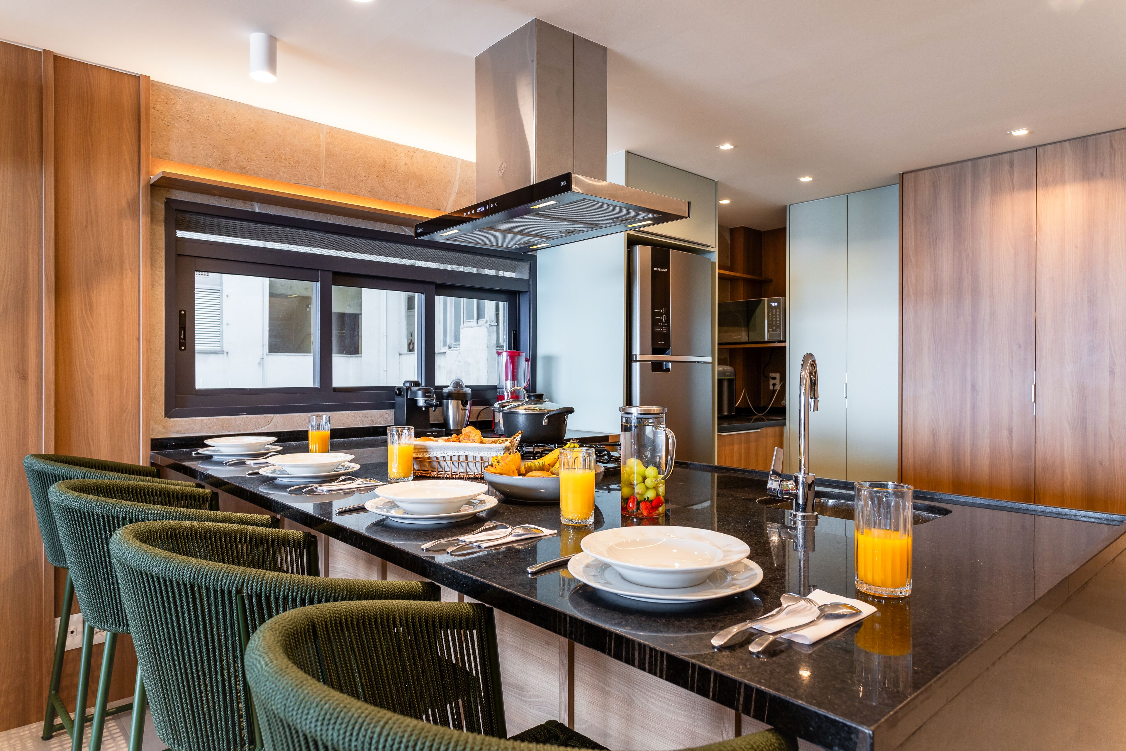 A modern kitchen with a central island, bar stools, and a large window.