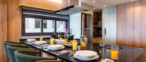 Una cocina moderna con una isla central, taburetes de bar y un amplio ventanal.