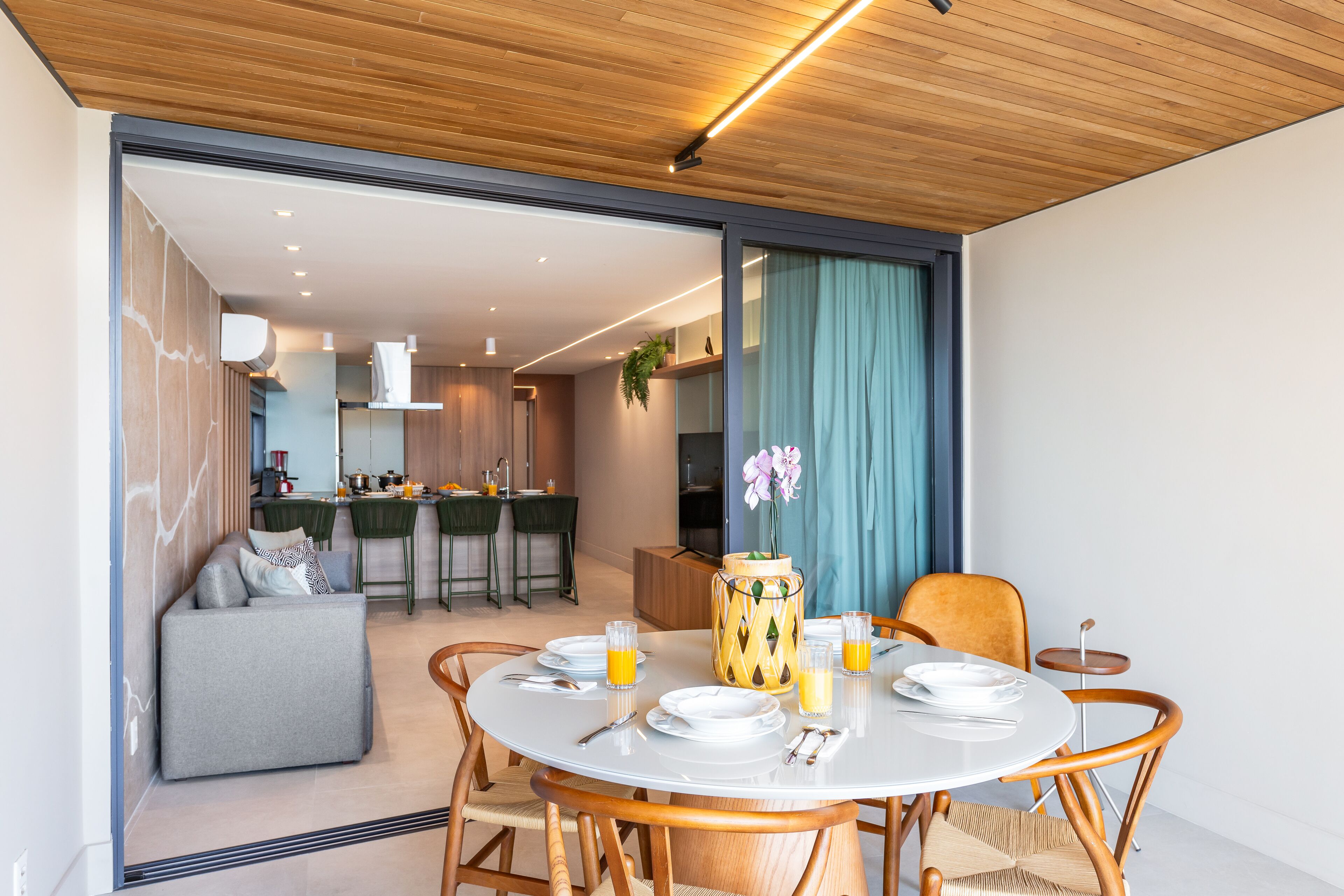 Un comedor moderno con una mesa redonda, sillas y un jarrón con flores.