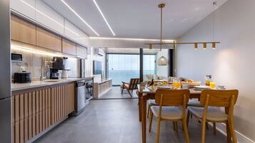 Una cucina moderna con mobili in legno, un'area pranzo con sedie di legno e vista all'esterno.