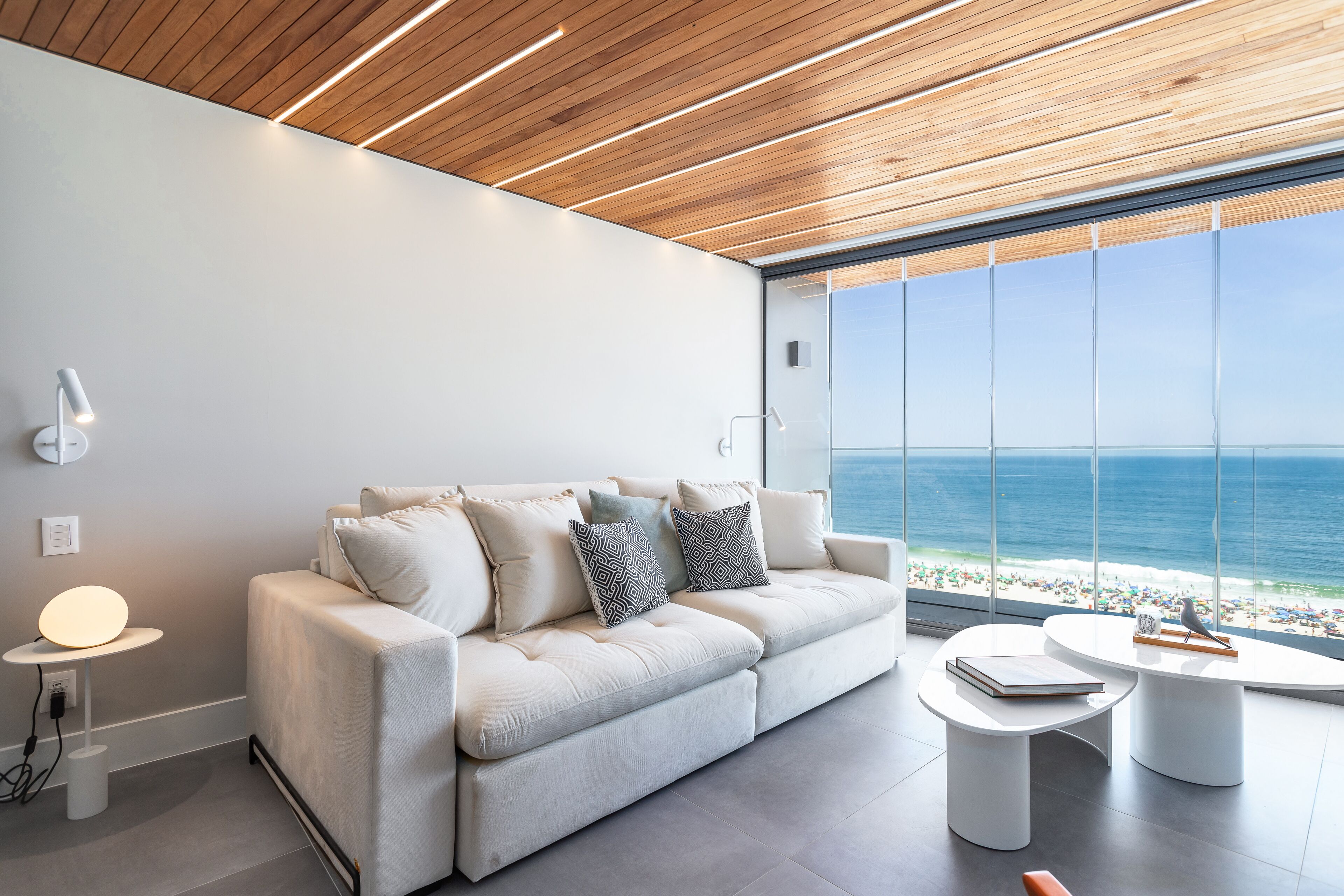 Una sala de estar moderna con un sofá blanco, dos mesitas auxiliares y vistas al océano.