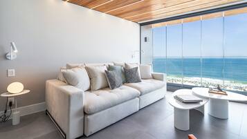 Una sala de estar moderna con un sofá blanco, dos mesitas auxiliares y vistas al océano.