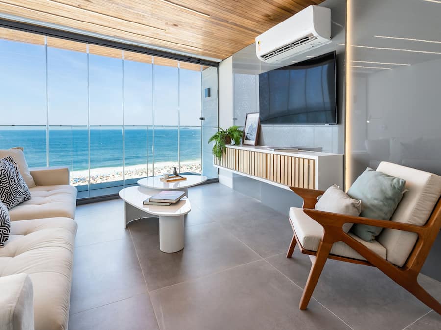 A modern living room with a large window overlooking the beach, a sofa, a coffee table, and a TV.