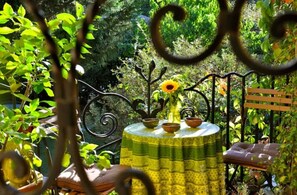 A round table with a patterned tablecloth, a vase with a sunflower, and a bench. - Villa de Reve Avec Jardin, Piscine et Option Spa (Uzès)