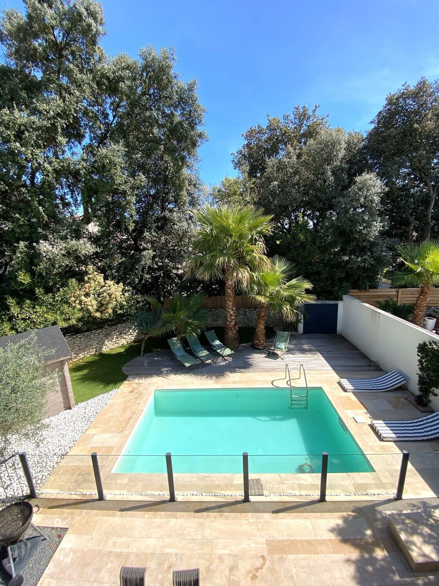Ein rechteckiger Swimmingpool mit klarem, blauem Wasser, umgeben von einer Steindeck.