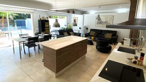 A modern kitchen with a central island, a dining area with a table and chairs, and a view of a swimming pool.