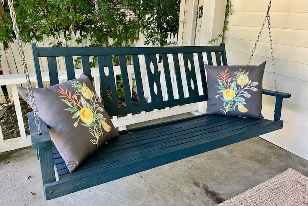 Un banc en bois vert foncé agrémenté de coussins à motifs floraux.