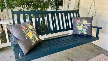 Un banc en bois vert foncé agrémenté de coussins à motifs floraux.