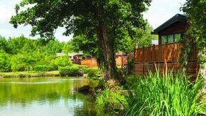 Una cabaña junto al lago con una terraza de madera y vistas al agua.