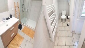 Un baño moderno con cabina de ducha de vidrio, inodoro blanco y tocador de madera.
