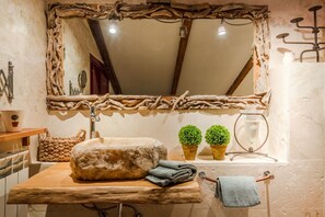 A rustic bathroom with a wooden vanity, a large mirror with a natural frame, and a towel rack. - The Rooftop Penthouse (Lucca)