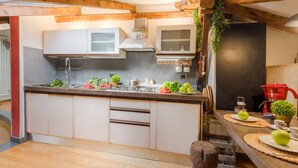 A modern kitchen with white cabinets, a central island, and wooden beams. - The Rooftop Penthouse (Lucca)