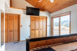 Un dormitorio con cama, armario de madera y televisor montado en la pared.