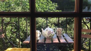 A balcony with a table, two yellow cushioned chairs, and a decorative metal railing. - Maisonnette Avec Terrasse Dentrée et Balcon (Uzès)