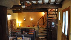 A cozy living room with a sofa, a coffee table, and a staircase leading to a balcony. - Maisonnette Avec Terrasse Dentrée et Balcon (Uzès)