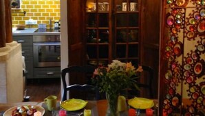 A dining area with a wooden table set for two, a vase with flowers, and a decorative mirror with circular patterns. - Maisonnette Avec Terrasse Dentrée et Balcon (Uzès)