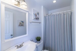 A bathroom with a white sink, a mirror, a towel rack, and a striped shower curtain.