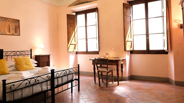 Ein Schlafzimmer mit Bett, Nachttisch, Lampe und Schreibtisch mit Stuhl.