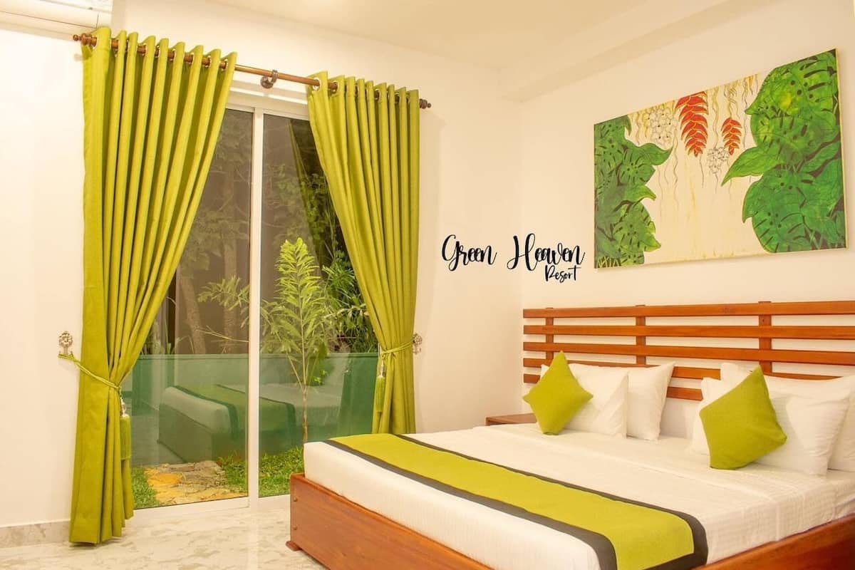 A bedroom with a bed, green curtains, a glass door, and a painting on the wall.