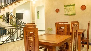 Un comedor con una mesa y sillas de madera, una escalera y una pared decorada con platos y un cuadro.