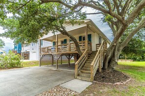 A two-story house with a wooden deck and a staircase leading to a covered porch. - Pet-friendly oceanside home in Nags Head by Sun Realty (Nags Head)