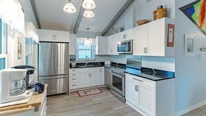 A modern kitchen with stainless steel appliances, white cabinetry, and a wooden countertop.