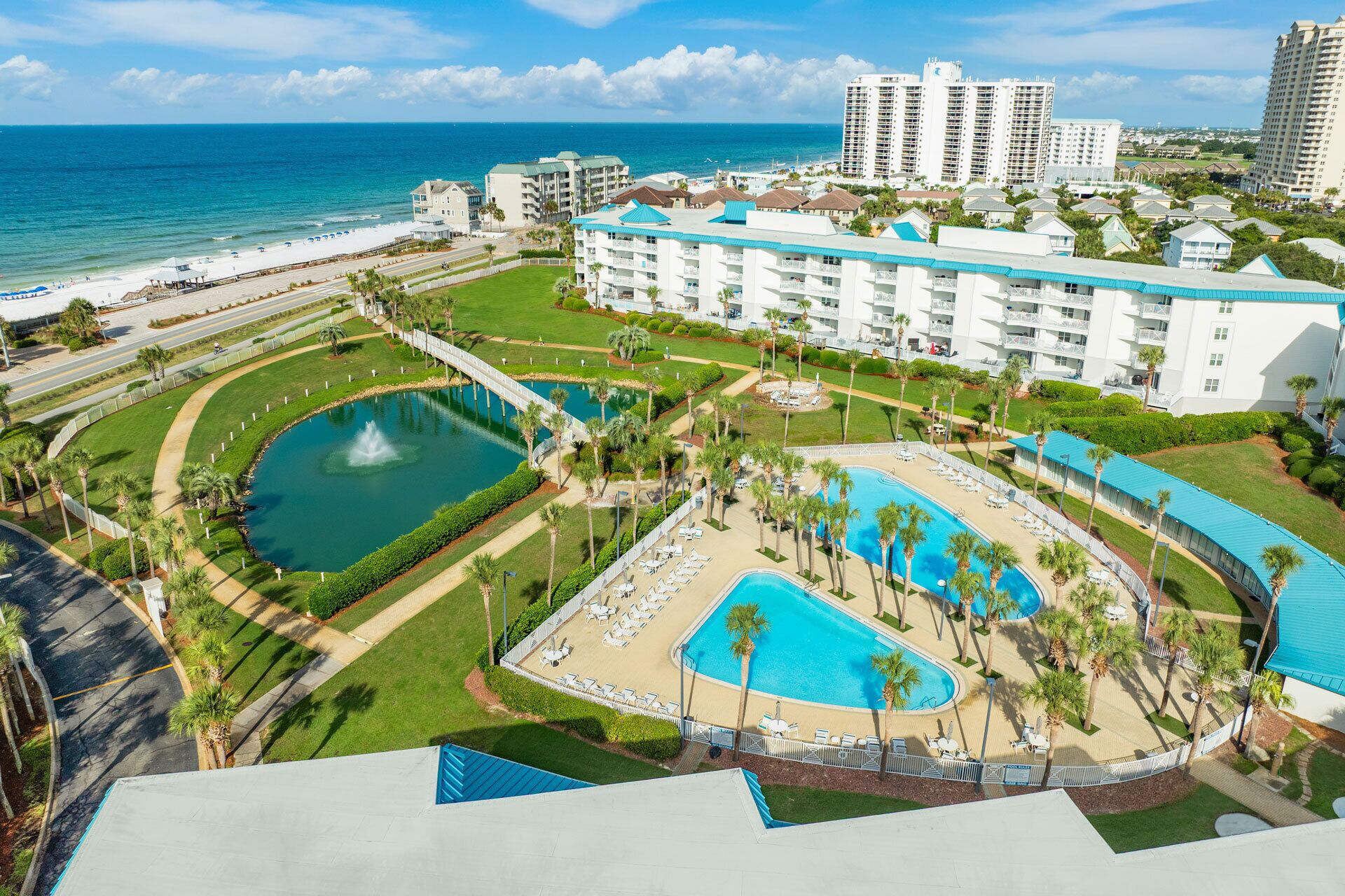 Un resort con varias piscinas, un puente y vista al océano.