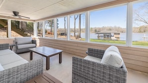 A covered patio area with wicker furniture, a ceiling fan, and a view of a lake and trees. - Hot Tub, Boat Dock, Large Deck, Firepit, Tiki bar, Pool! (Littleton)