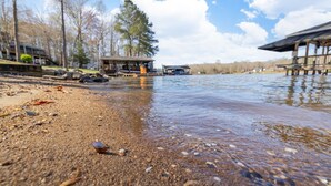 A lakeside view with a wooden dock extending into the water, surrounded by trees and a clear sky. - Hot Tub, Boat Dock, Large Deck, Firepit, Tiki bar, Pool! (Littleton)
