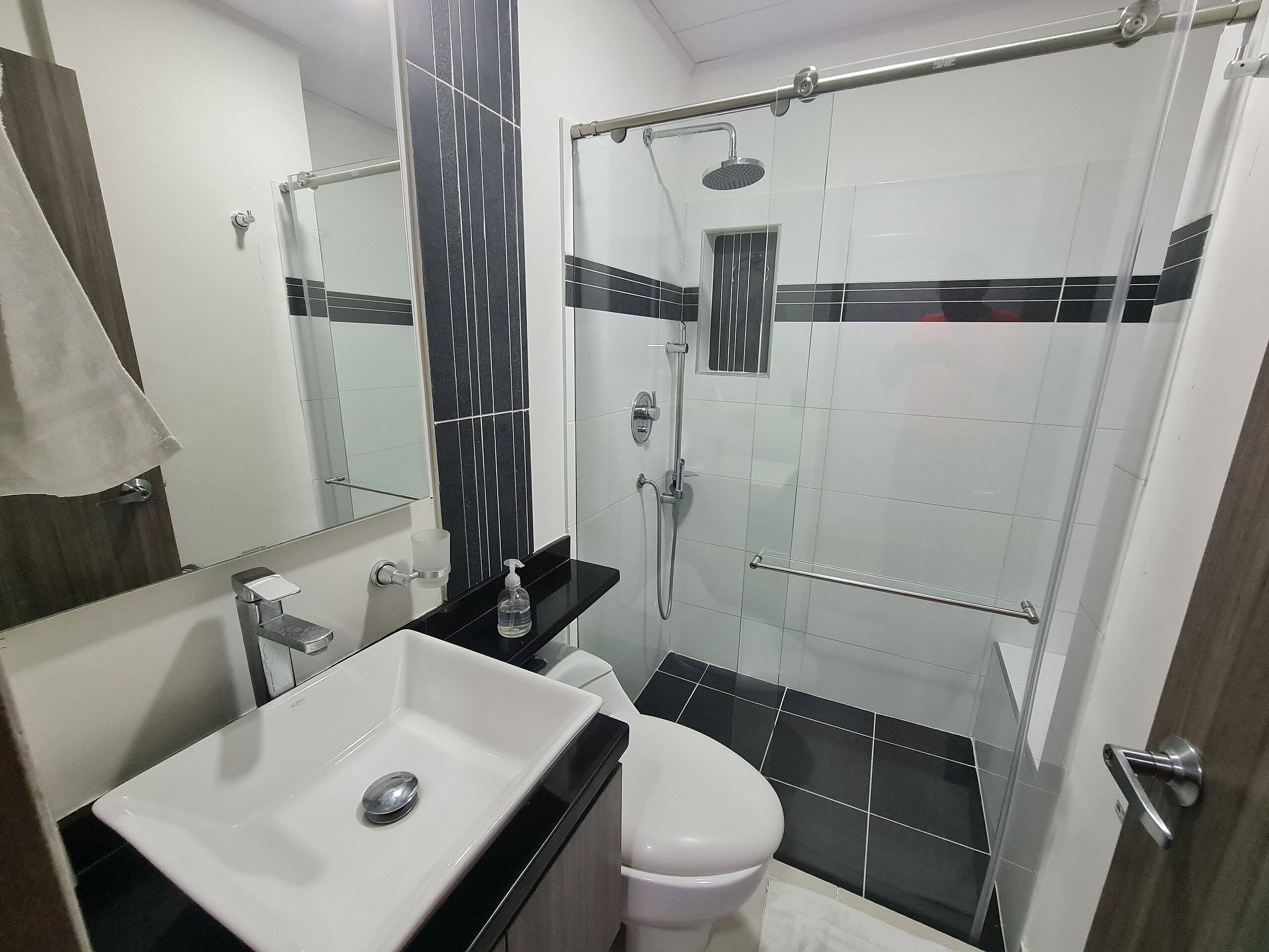 Une salle de bain avec un lavabo blanc, des toilettes et un espace douche.