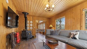 A cozy cabin interior with a wooden interior, a fireplace, a sofa, and a television. - Game Room | Scenic Views | Cozy Fireplace (Grand Lake)