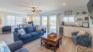 A spacious living area with a blue sofa, a wooden coffee table, and a ceiling fan. - Gorgeous pet-friendly oceanfront duplex in Nags Head w/ a hot tub & rec room (Nags Head)