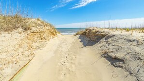 A sandy beach path leading to the ocean with sparse vegetation on either side. - Gorgeous pet-friendly oceanfront duplex in Nags Head w/ a hot tub & rec room (Nags Head)