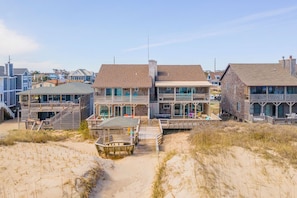 A beachfront property with multiple buildings, a wooden deck, and a sandy beach area.