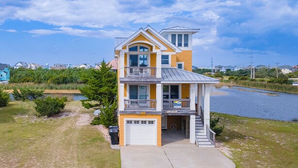 A two-story house with a balcony, a garage, and a view of a lake. - Pet-friendly canalfront home in Avon w/ private pool and hot tub! (Avon)