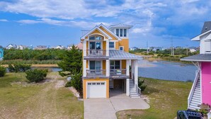 A two-story house with a balcony, a garage, and a waterfront view. - Pet-friendly canalfront home in Avon w/ private pool and hot tub! (Avon)