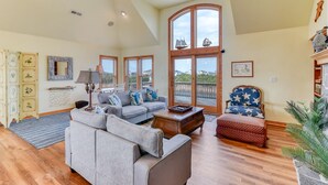A spacious living room with a high ceiling, large windows, and a view of the outdoors. - Pet-friendly canalfront home in Avon w/ private pool and hot tub! (Avon)