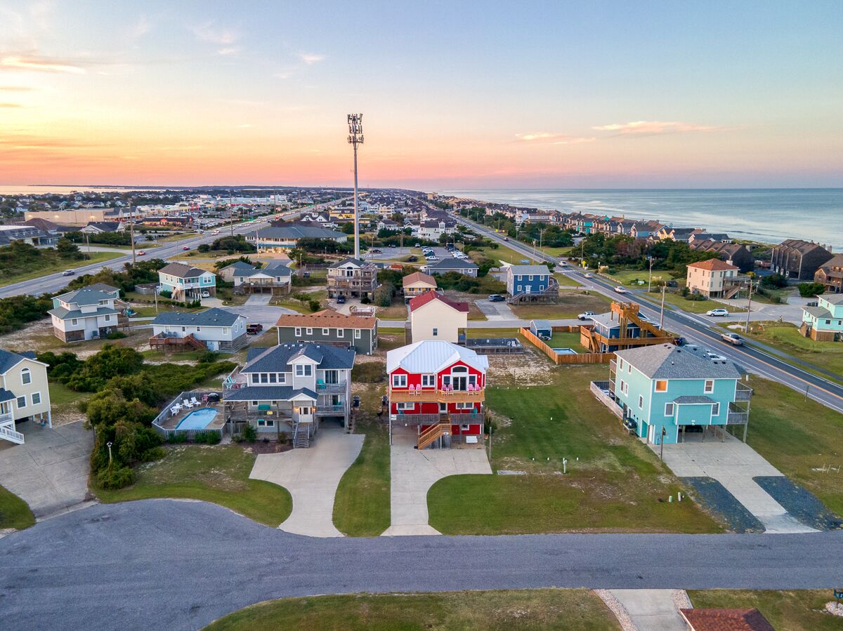 Una zona residenziale sul lungomare, con case e un edificio rosso ben visibile, e una vista aperta sull'oceano.