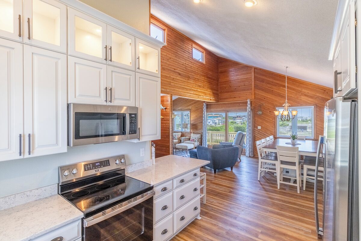 Eine moderne Küche mit weißen Schränken, einer eingebauten Mikrowelle und einem Edelstahlbackofen.
