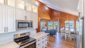 Una cocina moderna con gabinetes blancos, un microondas empotrado y un horno de acero inoxidable.