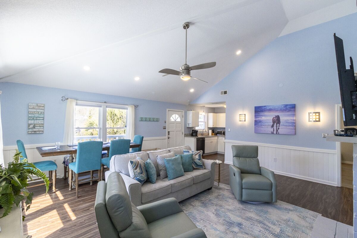 A spacious living room with a sofa, chairs, and a dining area.